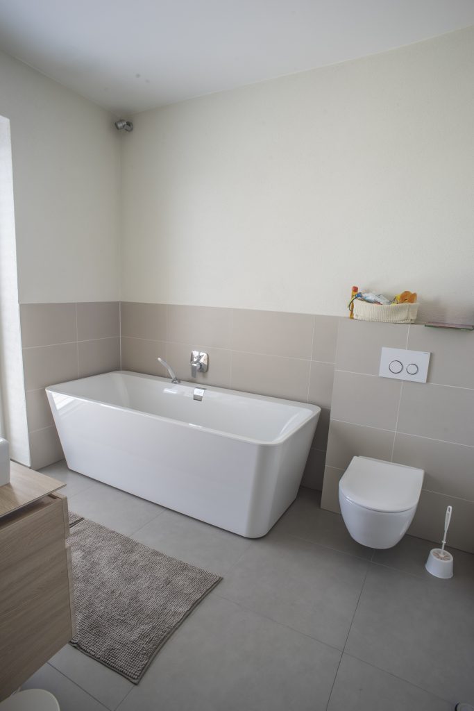 Modernes Bad mit beigen Fliesen bis zur Hälfte der Höhe des Raumes.