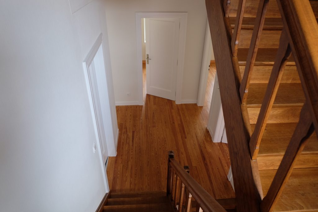 Blick von oben in ein Treppenhaus mit einer abgeschliffenen und aufbereiteten alten Holztreppe.