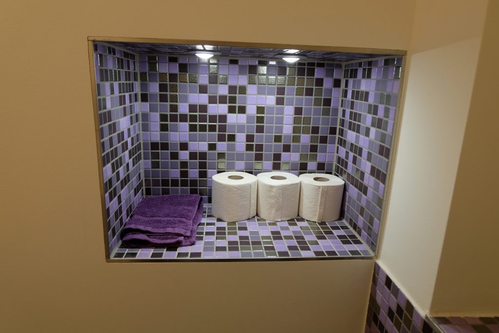 Duschablage in einer Nische, gefliest mit lila Mosaik.