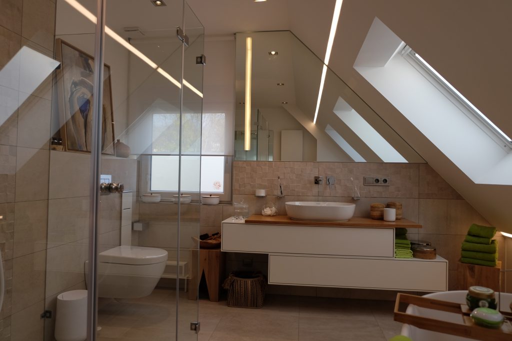 Gemütliches Badezimmer im Dachgeschoss mit großzügigem modernen Waschtisch und einem großen maßgeschneiderten Spiegel.