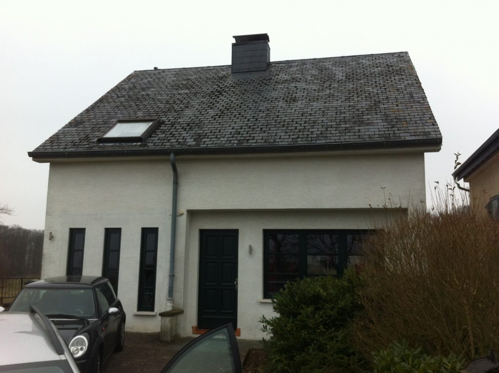 Weiß gestrichenes Einfamilienhaus mit schwarzem Satteldach.