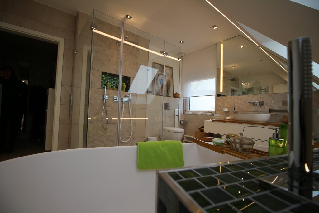 Gemütliches Badezimmer im Dachgeschoss mit naturfarbenen Fliesen und einer großen Dusche aus Glas