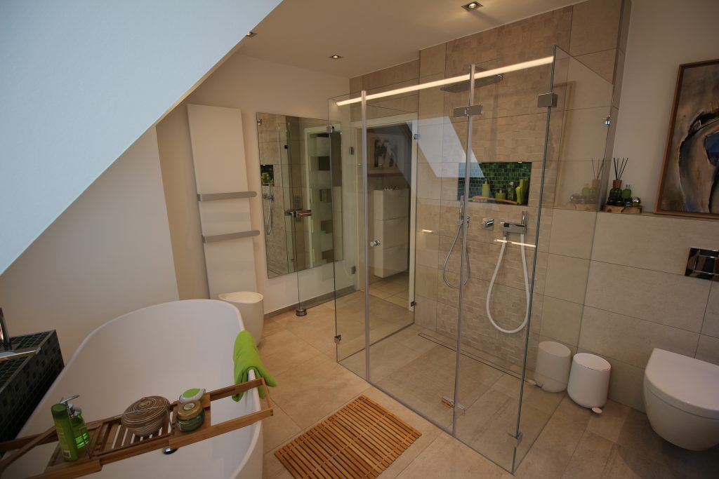 Gemütliches Badezimmer im Dachgeschoss mit indirektem Licht, einer bodentiefen Dusche aus Glas und einer freistehenden Badewanne.