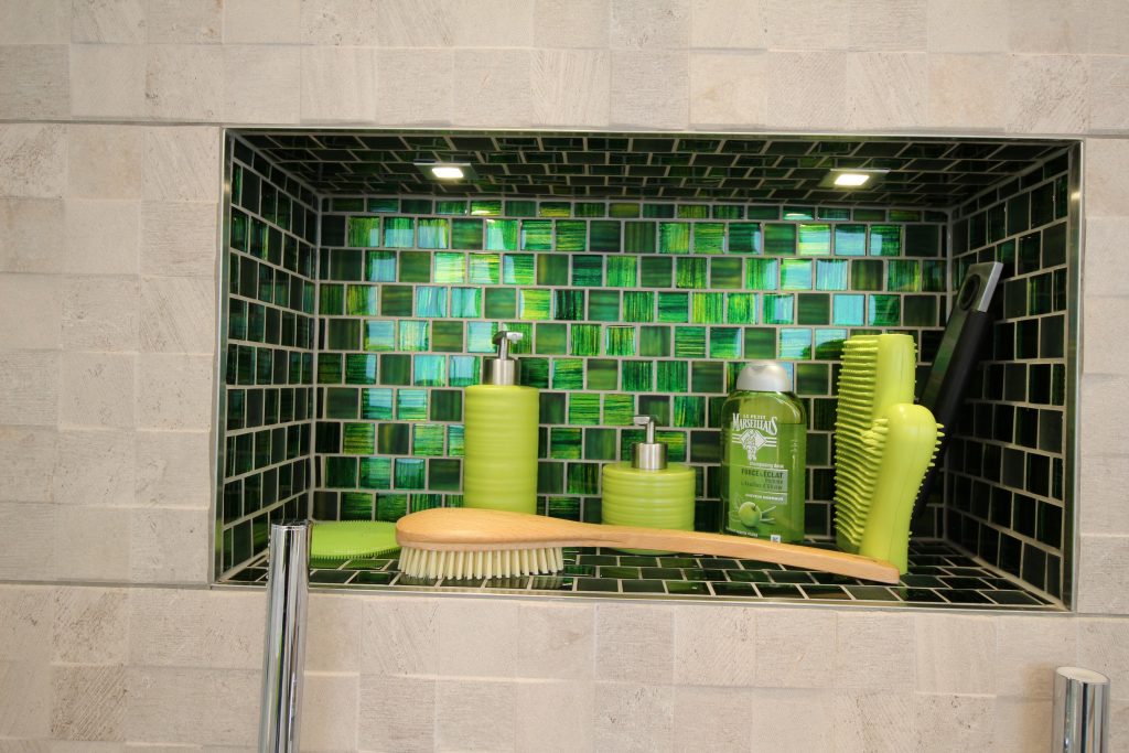 Nische als Duschablage, die mit grünem Mosaik gefliest ist.