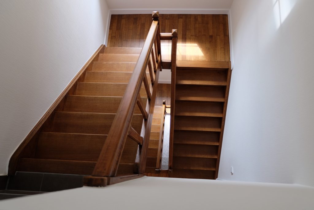 Blick von oben in ein Treppenhaus mit einer abgeschliffenen und aufbereiteten alten Holztreppe.