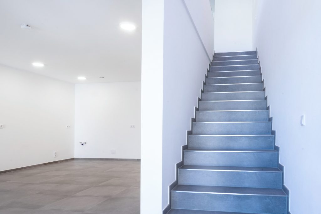 Sich in einer Wohnung befindende schieferfarbene Treppe mit silbernen Leistenelementen.