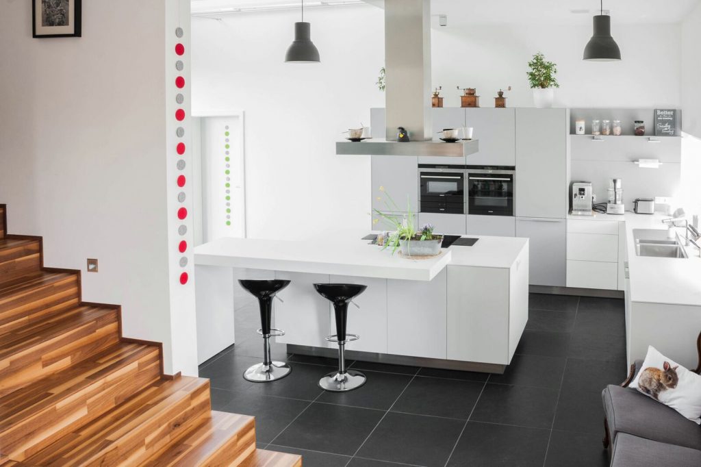 Helle Moderne L-förmige Küche mit Kücheninsel und schwarzen Barhockern.